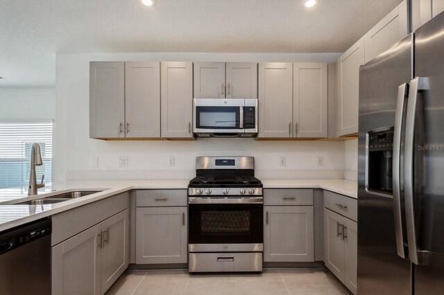 kitchen featuring appliances with stainless steel finishes, light tile patterned flooring, sink, and gray cabinets