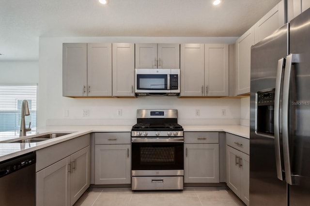 kitchen with sink, light tile patterned floors, gray cabinets, and appliances with stainless steel finishes