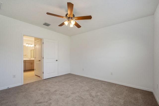 unfurnished bedroom with ceiling fan, light colored carpet, and ensuite bathroom