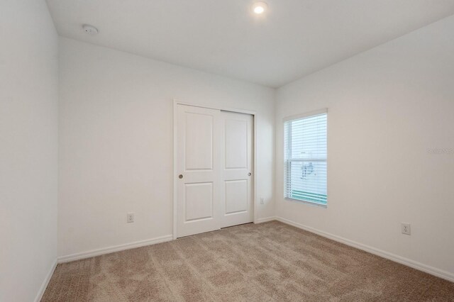 unfurnished bedroom featuring light carpet and a closet