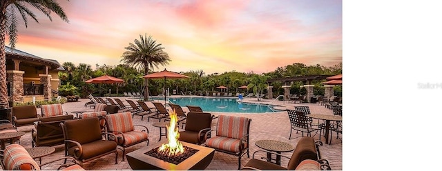 pool at dusk featuring a patio area