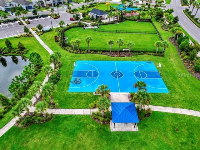 view of sport court with a lawn and a water view