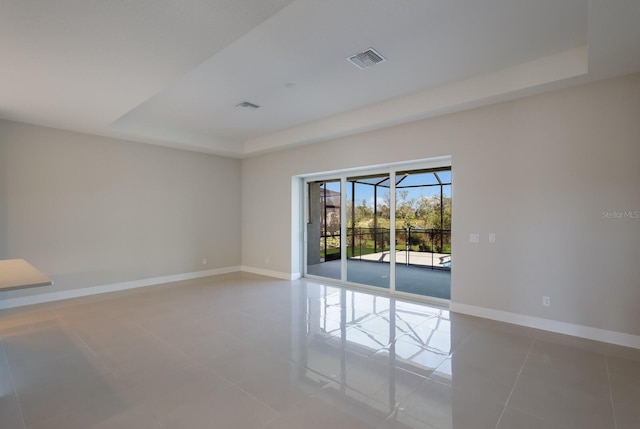 tiled empty room featuring a raised ceiling