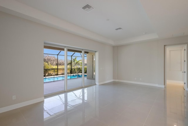 unfurnished room featuring a tray ceiling and light tile patterned floors