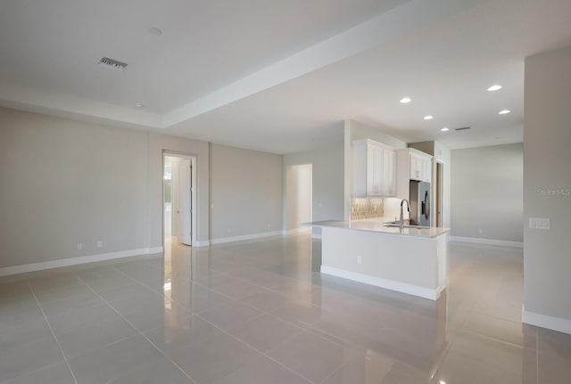 unfurnished living room featuring sink and light tile patterned flooring