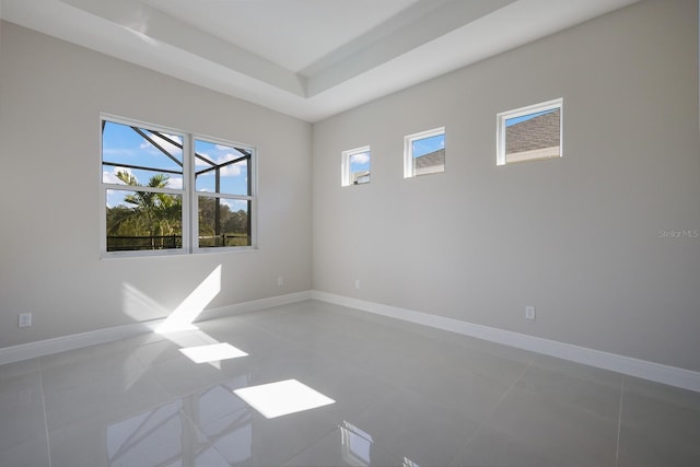 spare room featuring tile patterned floors and a raised ceiling