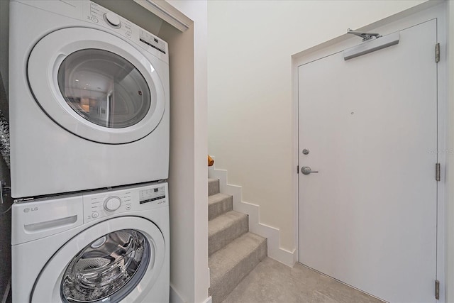 laundry area with stacked washer / dryer and light tile patterned floors