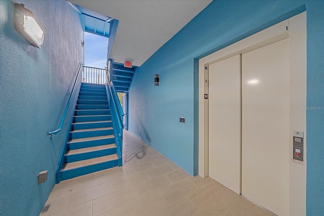 corridor with elevator, a textured wall, and stairway