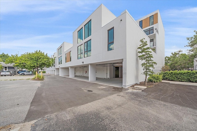 view of building exterior featuring covered parking and fence