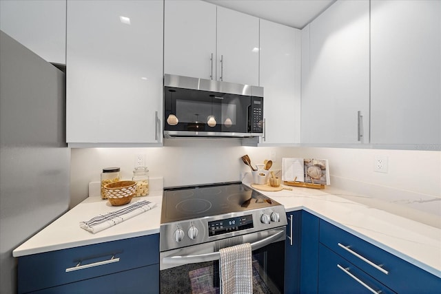 kitchen with light stone countertops, white cabinets, appliances with stainless steel finishes, and blue cabinets