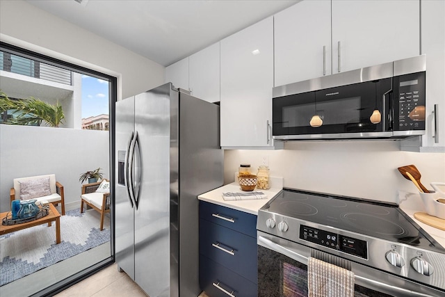 kitchen featuring light tile patterned floors, white cabinets, appliances with stainless steel finishes, and blue cabinetry