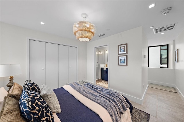 bedroom featuring a closet, light tile patterned flooring, and connected bathroom