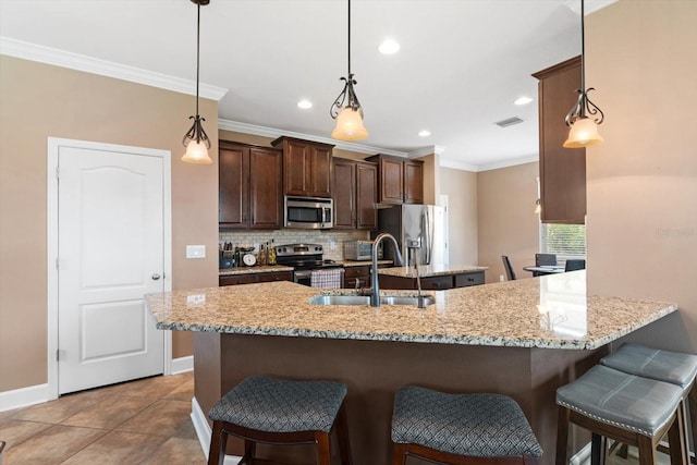 kitchen with tile patterned flooring, stainless steel appliances, sink, and pendant lighting