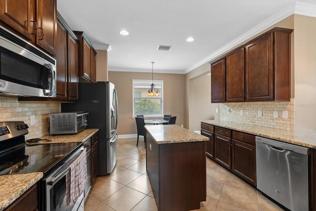 kitchen featuring appliances with stainless steel finishes, backsplash, a center island, decorative light fixtures, and ornamental molding