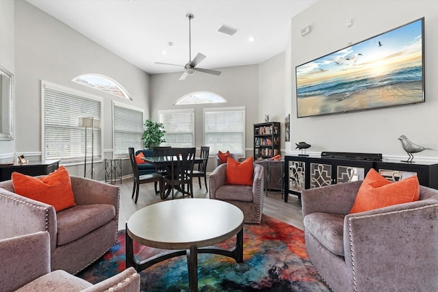 living room featuring a towering ceiling, wood-type flooring, and ceiling fan