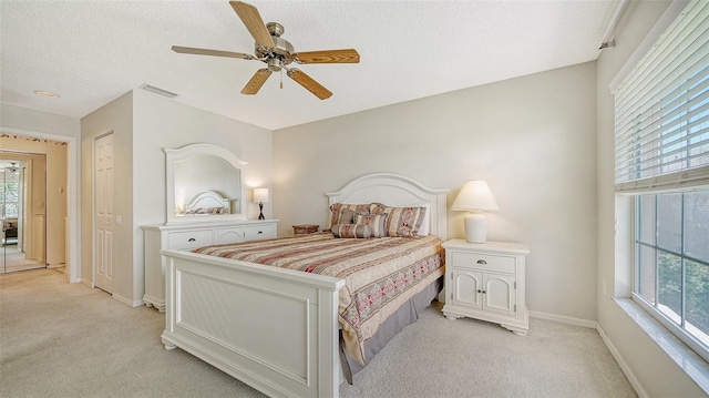 bedroom with light colored carpet, ceiling fan, and a textured ceiling