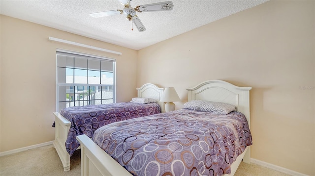 bedroom with ceiling fan, light carpet, and a textured ceiling