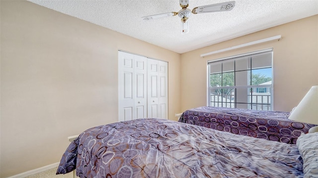 bedroom with a textured ceiling, carpet flooring, ceiling fan, and a closet