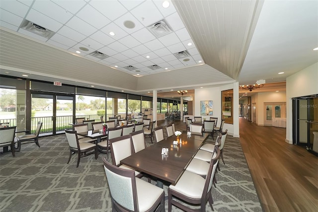 interior space featuring dark hardwood / wood-style floors, a notable chandelier, and a drop ceiling