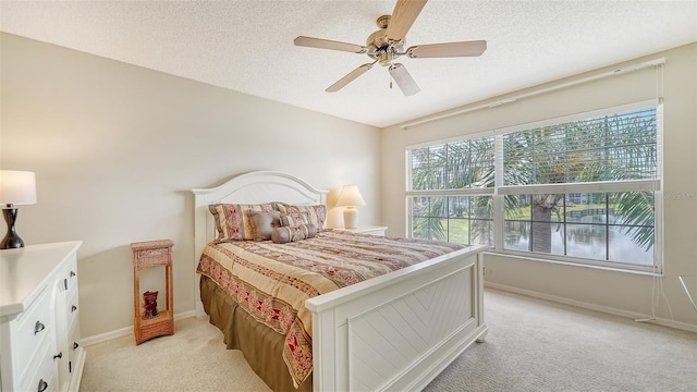 carpeted bedroom with ceiling fan and a textured ceiling