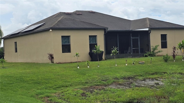 back of house featuring a sunroom and a lawn