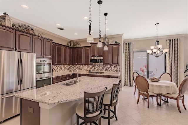 kitchen with dark brown cabinetry, stainless steel appliances, a kitchen island with sink, crown molding, and sink