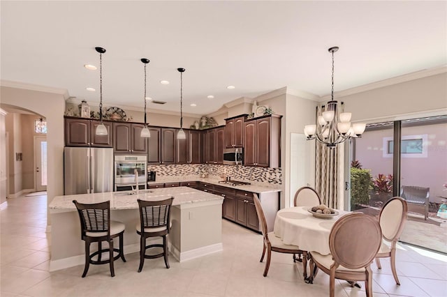 kitchen featuring a center island with sink, pendant lighting, dark brown cabinetry, and stainless steel appliances