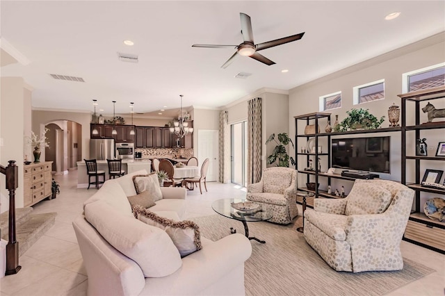 living room featuring ceiling fan with notable chandelier, crown molding, and light tile patterned flooring