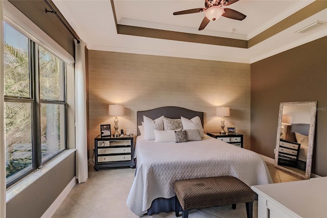 bedroom with ceiling fan, wood walls, ornamental molding, and a tray ceiling