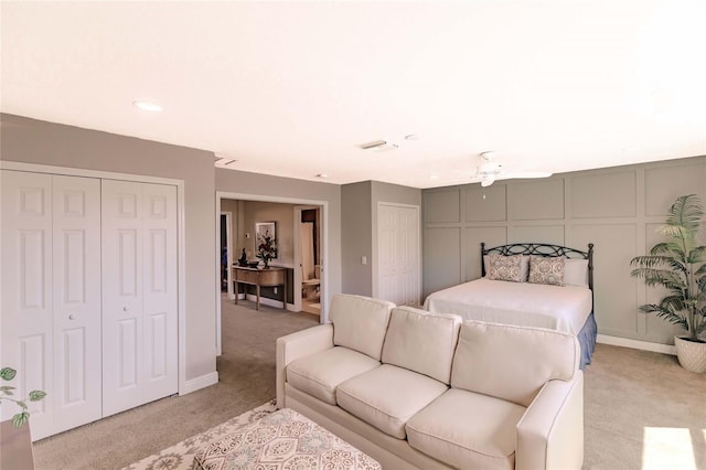 carpeted bedroom featuring ceiling fan and two closets