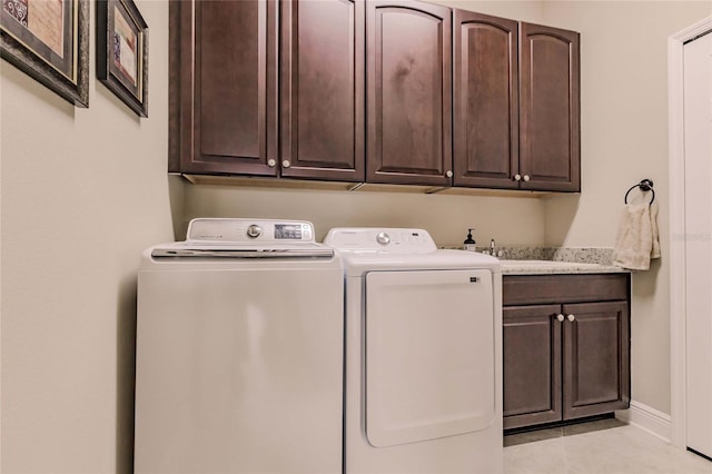 laundry room featuring cabinets, light tile patterned floors, sink, and washing machine and clothes dryer