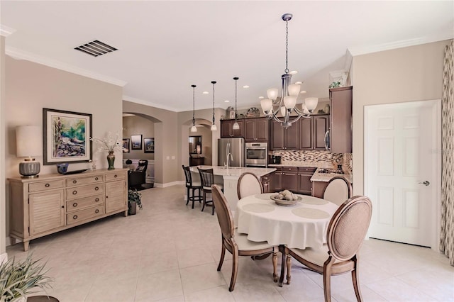 tiled dining area featuring ornamental molding and a notable chandelier