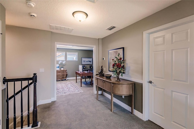 hall featuring carpet and a textured ceiling