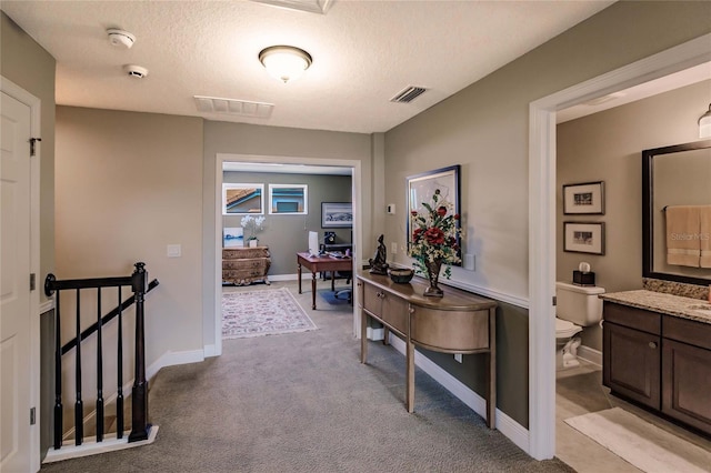 hallway with light colored carpet and a textured ceiling