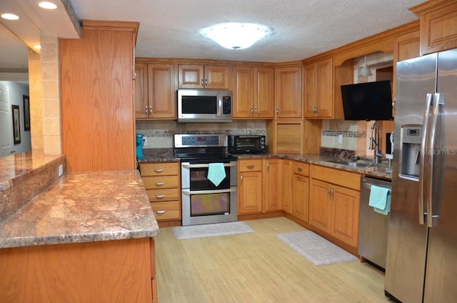 kitchen with light hardwood / wood-style floors, sink, decorative backsplash, and stainless steel appliances