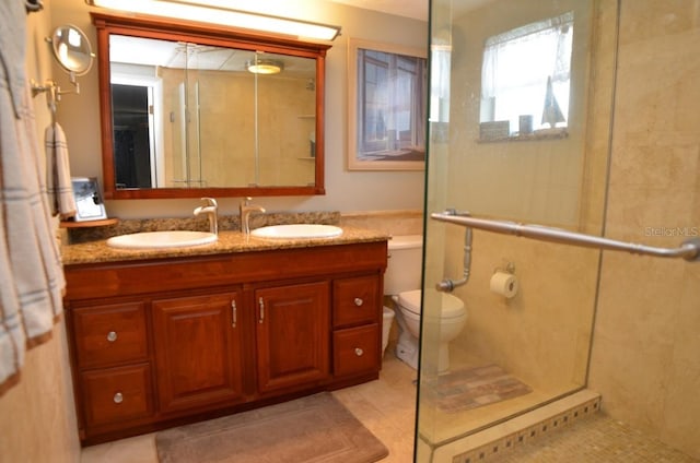 bathroom with dual vanity, tile patterned floors, an enclosed shower, and toilet