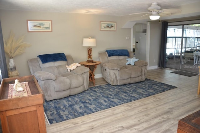 living room with light hardwood / wood-style floors, a textured ceiling, and ceiling fan