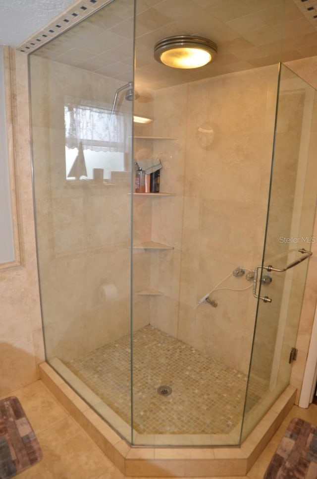 bathroom with a shower with shower door and tile patterned floors