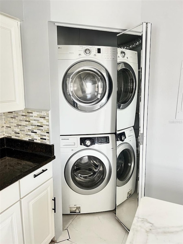 washroom with stacked washing maching and dryer and light tile patterned floors