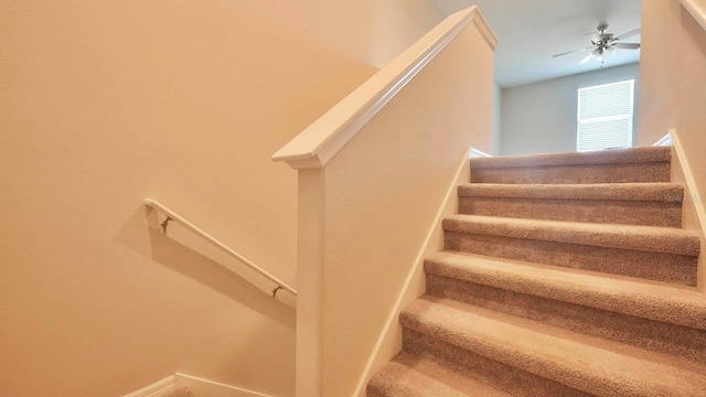 stairway featuring ceiling fan