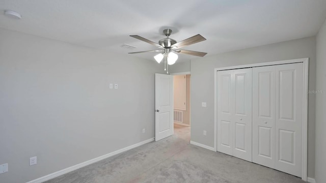 unfurnished bedroom featuring ceiling fan, a closet, and light carpet