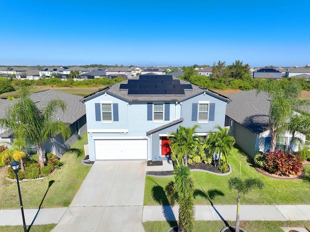 front of property featuring solar panels, a garage, and a front lawn