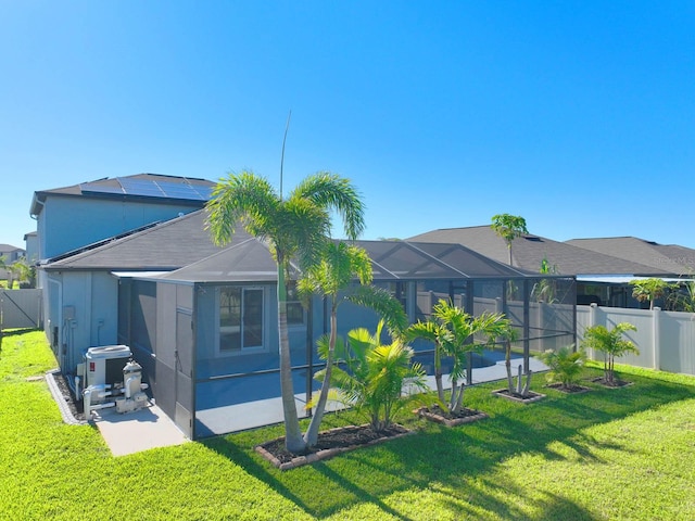 rear view of property with glass enclosure, a yard, and a patio