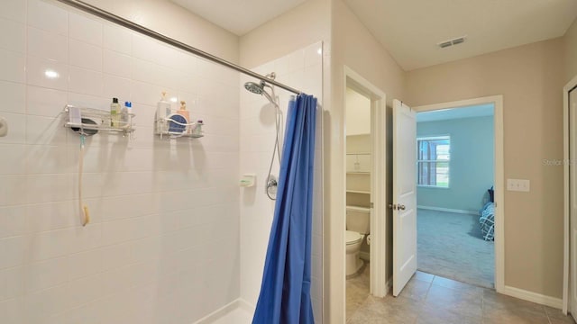 bathroom with tile patterned floors, walk in shower, and toilet