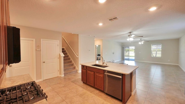 kitchen with stainless steel dishwasher, a textured ceiling, ceiling fan, a kitchen island with sink, and sink