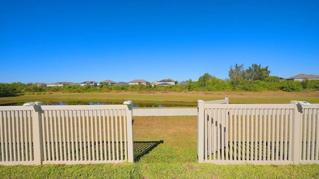 view of gate featuring a water view and a lawn