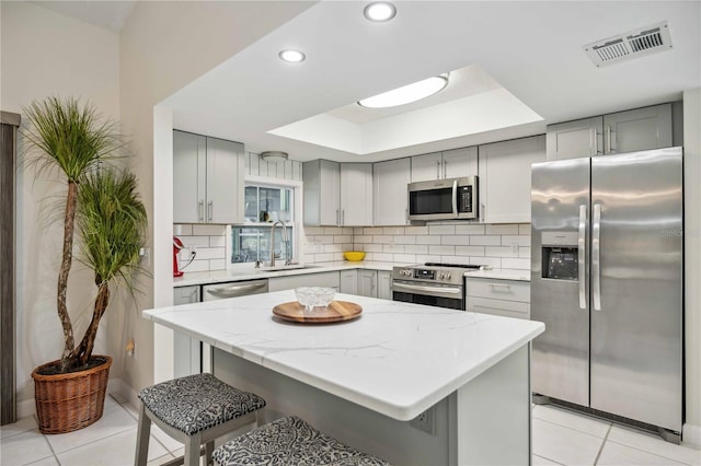 kitchen featuring a center island, stainless steel appliances, a kitchen bar, and light tile patterned floors