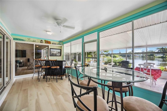 sunroom featuring a water view and ceiling fan