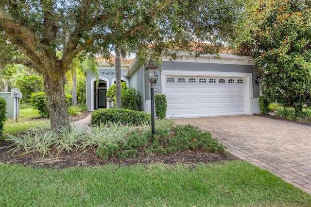 view of front of house featuring a garage, a tiled roof, decorative driveway, and stucco siding