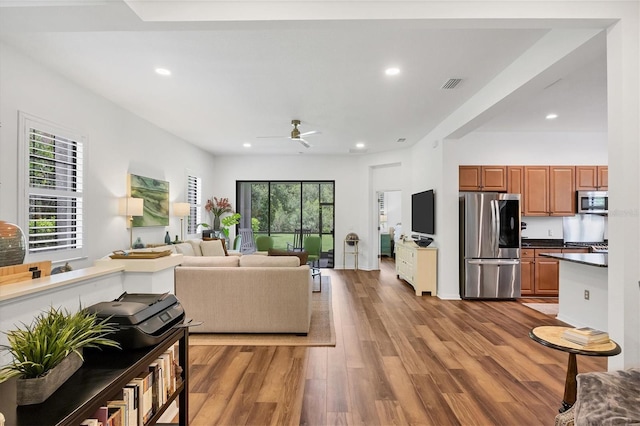 living room with light wood finished floors, a wealth of natural light, visible vents, and recessed lighting